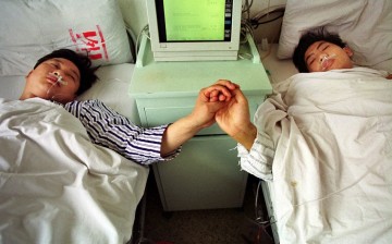 Chinese brothers Sun Fusheng (L) and Sun Baosheng hold hands after China's first live nationwide television broadcast of a kidney transplant operation in Wuhan.