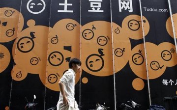 An employee walks past the logo of Youku Tudou at the company's headquarters in Beijing, China.