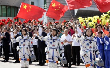 Three Chinese astronauts wave to the crowd before boarding the Shenzhou-9 that will bring them to an orbiting space module.
