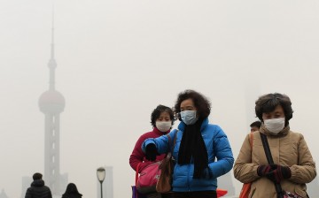 Women wear face masks in front of the Oriental Pearl TV Tower during a hazy day in downtown Shanghai, Jan. 26, 2015.