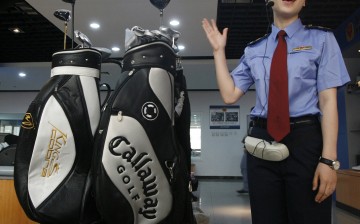 An officer talks beside confiscated counterfeit golf clubs during a presentation in Beijing. Chinese regulators have been putting increasing pressure on businesses over fake goods.