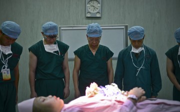 Nurses bow as they pay a silent tribute to a deceased patient who was willing to donate her organs at a hospital in Guangzhou, Guangdong Province, Nov. 22, 2012.