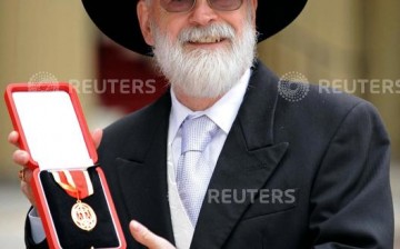 British author Terry Pratchett poses for photographers after receiving his knighthood from Britain's Queen Elizabeth at Buckingham Palace in London February 18, 2009