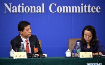 An interpreter (R) works at a press conference given by Zhu Weiqun, Huang Jiefu, Hu Xiaoyi, Li Yanhong, Yu Minhong, members of the 12th CPPCC.