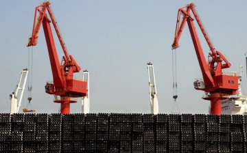 Piles of steel pipes to be exported are seen in front of cranes at a port in Lianyungang, Jiangsu Province, March 7, 2015. 