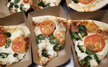 Several yummy pizzas, which can be part of a high-fat diet, are placed in paper holders.