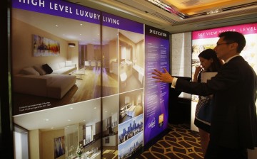 A sales representative speaks to a visitor in front of photographs of a London upmarket property development for sale, inside a luxury hotel in Hong Kong.