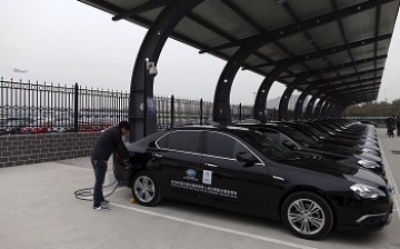 A man charges the batteries of BAIC Motors electric cars at a charging station at the Beijing Capital International Airport in Beijing.