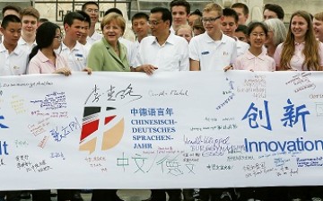 German Chancellor Angela Merkel and Premier Li Keqiang join Chinese and German high school students holding a symbolic banner for an education and language exchange program in July 2014.