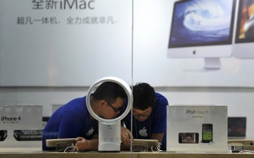 Employees at a fake Apple Store use an iPad tablet.