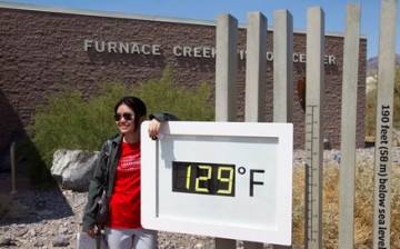 A student from China poses in front of an unofficial temperature gauge at the Furnace Creek Visitor Center in Death Valley National Park in California.