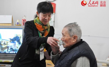 A man is assisted by Liang Huilan, the headed of Respite Care Service Team.