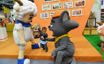A boy interacts with two cartoon figures during 2015 China International Cartoon and Animation Festival in Hangzhou, Zhejiang Province, on Tuesday, April 28, 2015. 