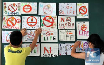 Children are posting anti-smoking banners on the wall as China's 