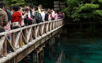 Crowds of tourists take photos on a bridge overlooking the Wuhua Hai Lake at Jiuzhai Valley National Park in China's Sichuan Province.