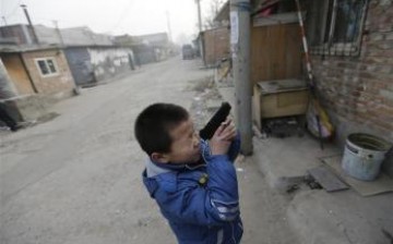 A child aims his toy gun at something as he plays in a poor neighborhood in Beijing.