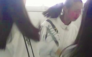 This still image from a video clip displays a female student in Quanzhou City being bullied by three other students.