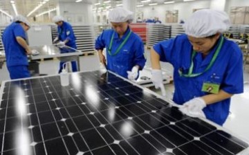 Workers clean solar panels at a solar panel assembly plant in Hangzhou.