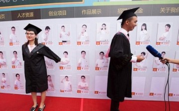 Two of Kunming University's new graduates pose for pictures with the profiles of excellent graduates for the Kunming University Talent Store on Taobao.