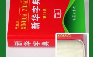 The 11th edition of the Xinhua Zidian with an inset photo showing how thick it is.