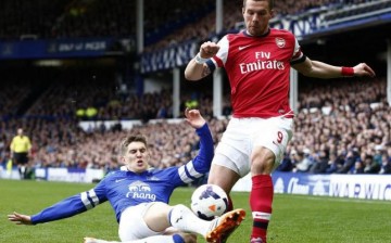 Everton's John Stones (L) challenges Arsenal's Lukas Podolski during their English Premier League soccer match.