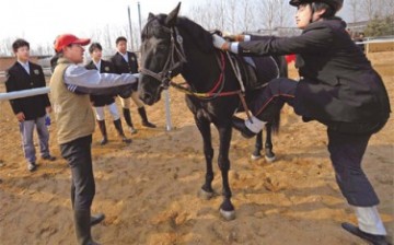 A student learns how to mount a horse from a trainer in a riding club in Changping.