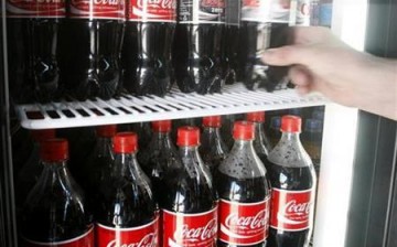 A customer takes a bottle of Coca-Cola from a grocery store fridge in Melbourne