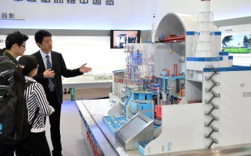 A staff member gives an introduction of the experimental fast reactor to visitors in front of a model during an exhibition in Beijing, China, April 15, 2014.