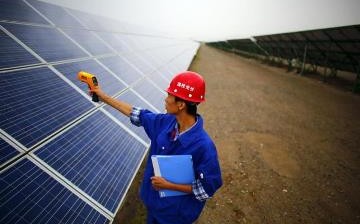 A worker inspects solar panels at a solar farm in Dunhuang, northwest of Lanzhou, Gansu Province.