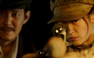 Jun Ji-hyun aims at a target while Lee Jung-jae observes in the background in the film 