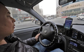 A taxi driver checks his two smartphones for potential customers in Beijing, Feb. 18, 2014. 