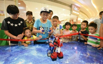 Children watch robots fight with each other at a robot show in Hefei, capital of east China's Anhui Province, Aug. 23, 2015. 