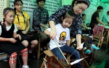 Primary school pupils in Shanghai learn how cotton spinning works at an exhibition of intangible cultural heritage in Xiangyang Park.