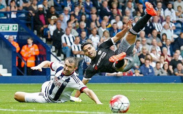 Chelsea's Radamel Falcao falls over West Brom’s Gareth McAuley on the pitch.