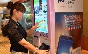 A staff member shows how to use a mobile phone to pay through a vending machine in Beijing, on June 9, 2013.