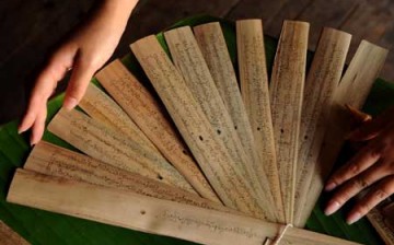 An artist presents newly finished palm-leaf manuscripts of Buddhist sutras in southwest China's Yunnan Province, April 14, 2009.