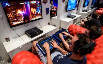 People play video games at the Sony Playstation stand at the Gamescom 2015 gaming trade fair during the media day on August 5, 2015 in Cologne, Germany.