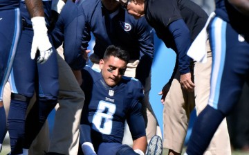 Tennessee Titans quarterback Marcus Mariota (#8) is being attended by medical staff after receiving a late and low hit from the Miami Dolphins.