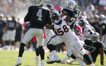 Oakland Raiders quarterback Derek Carr (#4) is sacked by Denver Broncos' Von Miller (#58).