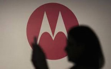 A user checking out her phone against the backdrop of the Motorola logo.