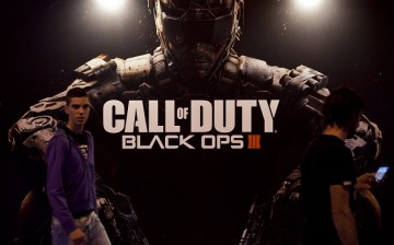 Fairgoers pass by a giant poster of last installment of Call of Duty from US video game publisher Activision and called 'COD: Black Ops III' during the Madrid Games Week
