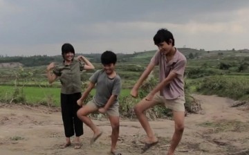 The brothers share some dance moves as their friend watches them in delight.