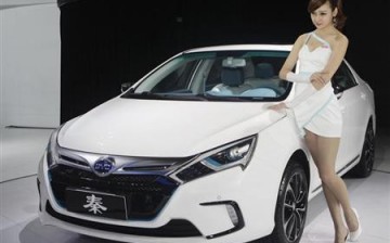 A model stands next to China's BYD QIN at Auto China 2012 in Beijing.