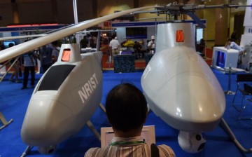 An exhibit attendee observes two Chinese-made drone helicopters in Beijing last year.