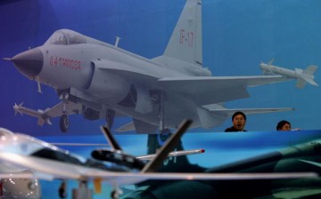 Visitors sit in front of an illustration of a Chinese-made JF-17 fighter jet at Airshow China 2006 in Zhuhai, south China's Guangdong Province, on Nov. 1, 2006.
