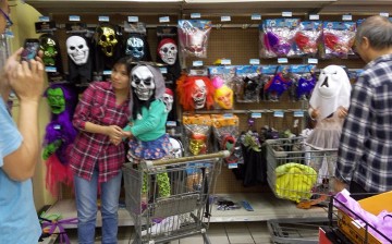 A mother carries her son while the boy wears a Halloween mask at a shopping store in Wuhan, Hubei Province, Oct. 26, 2015.