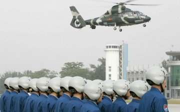 Outgoing Chinese People's Liberation Army (PLA) helicopter pilots watch as a helicopter full of new air force personnel arrives at a ceremony in Hong Kong on Nov. 25, 2007.