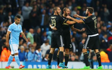 Juventus players celebrate their Champions League win against Manchester City as Sergio Aguero walks in the background.