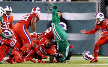 New York Jets running back Chris Ivory (in green) is tackled by Buffalo Bills defenders.