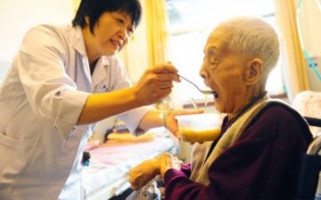 A caregiver attends to an elderly at a nursing home in Jinan, capital of Shandong Province.